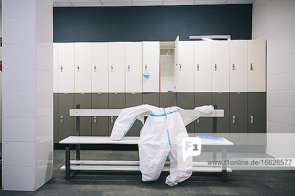 Protective wear and face shield kept on bench in locker room at hospital