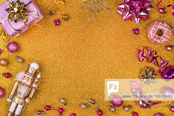 Studioaufnahme eines Weihnachtsgeschenks  eines altmodischen Nussknackers und verschiedener lilafarbener Weihnachtsdekorationen