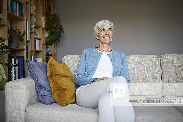 Smiling woman looking away while sitting at home