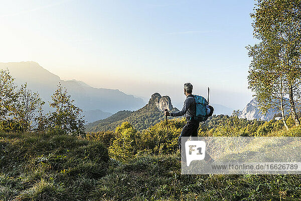 Male hiker walking on mountain against sky during sunrise  Orobie  Lecco  Italy