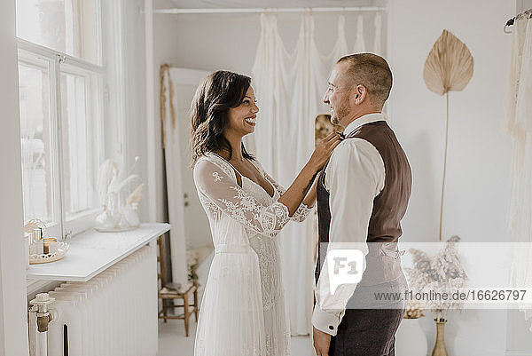 Lächelnde Braut  die sich zu Hause vor dem Bräutigam verbeugt