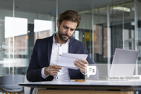 Geschäftsmann  der im Büro sitzend ein Dokument prüft