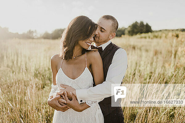 Couple embracing each other at field on sunny day