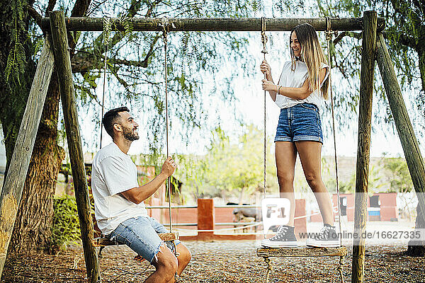 Junges Paar verbringt Zeit auf Schaukeln in einem öffentlichen Park