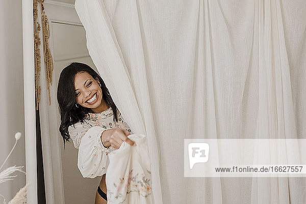 Lächelnde Braut beim Umkleiden hinter einem Vorhang