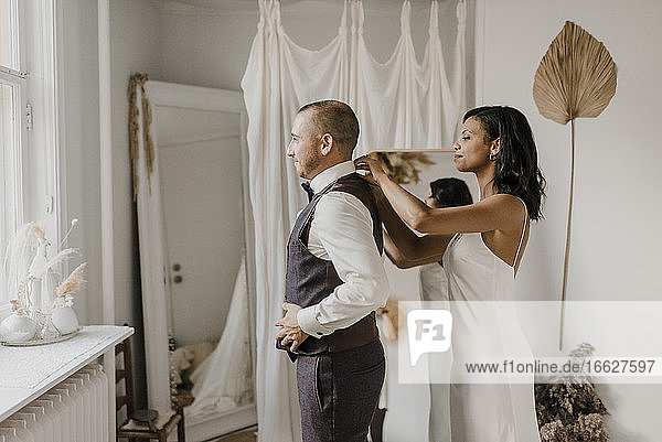 Junge Braut verbeugt sich vor dem Bräutigam  während sie zu Hause steht
