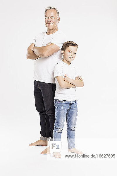 Vater und Sohn mit gekreuzten Armen posieren vor einem weißen Hintergrund