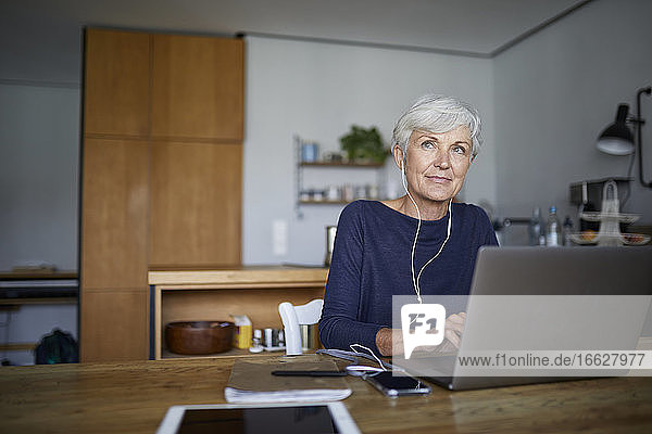 Ältere Frau arbeitet am Laptop  während sie zu Hause sitzt