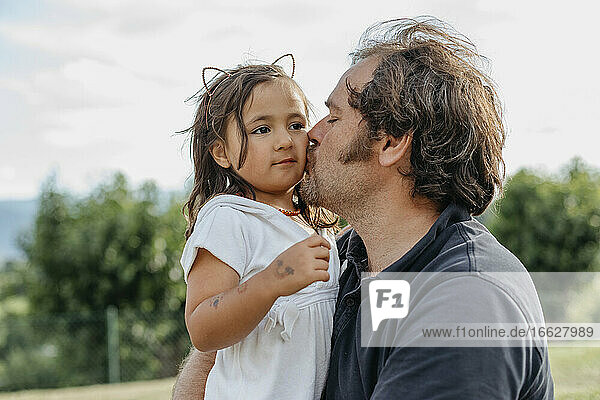 Vater küsst Tochter  während er im Hinterhof sitzt