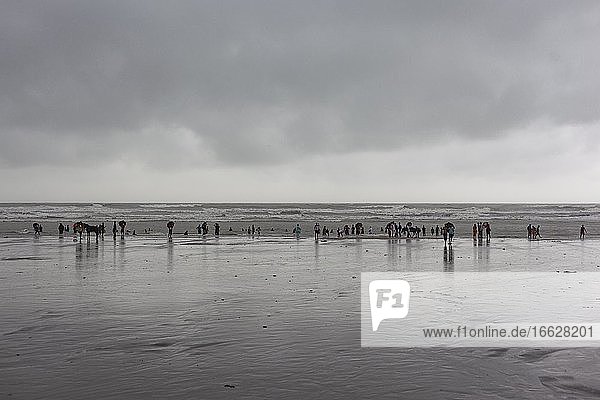 Bathers on the beach from Cox's Bazaar to monsoon rain  the beach at the Bay of Bengal in southeastern Bangladesh is considered with a length of 150 km as the longest natural beach in the world  Cox's Bazaar  Chittagong  Bangladesh  Asia