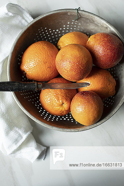 Blood oranges in a colander with a knife