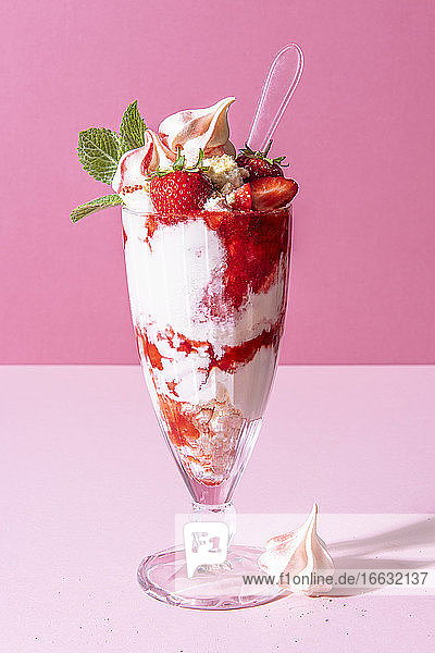 Strawberry sundae with ice cream  whipped cream  crushed meringue  strawberry sauce and mint