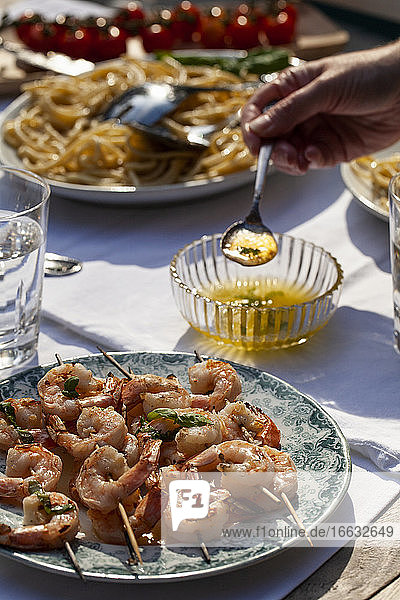 Shrimp skewers with basil butter sauce  pasta cacio e pepe (pasta with cheese and pepper) and tomatoes on an outdoor table