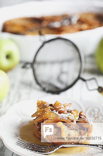 Apple French toast casserole with maple syrup and powdered sugar