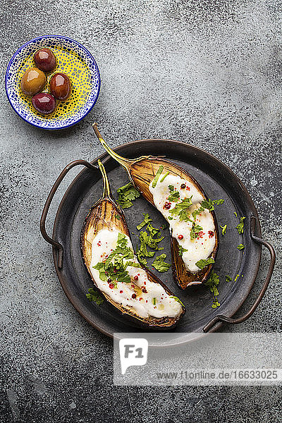 Grilled eggplant served in a pan with yoghurt  fresh cilantro and seasonings