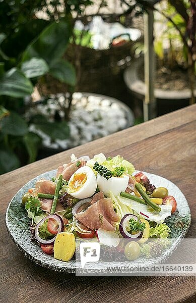 Gesunder rustikaler Bio-Salat nach Nicoise-Art mit Ei und Schinken im Freien.