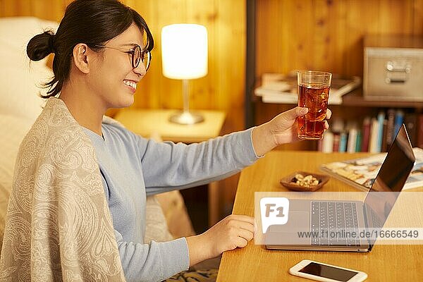 Japanische Frau  die zu Hause trinkt  trinkt aus der Ferne