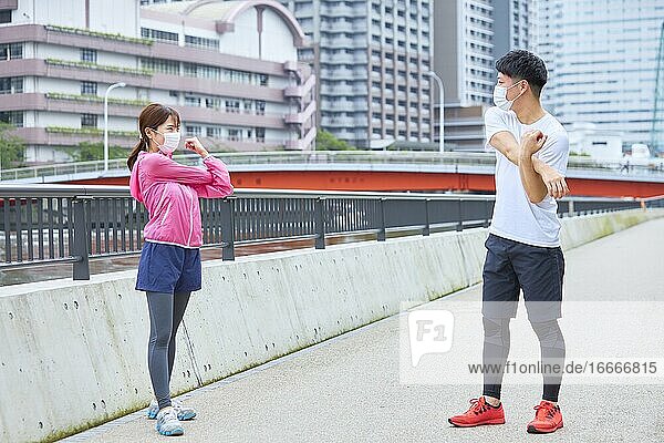 Young Man And Woman Stretching With A Face Mask