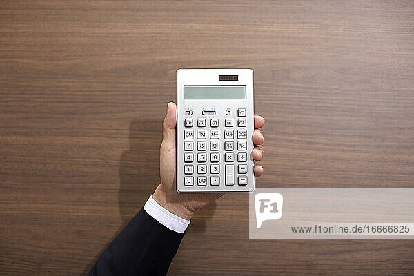 Hand Holding An Electronic Calculator