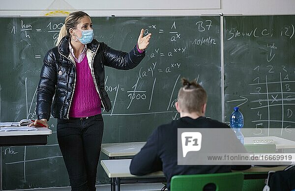 Teacher with winter jacket and face mask in classroom teaching gestures corona crisis Stuttgart Baden-Württemberg Germany Europe