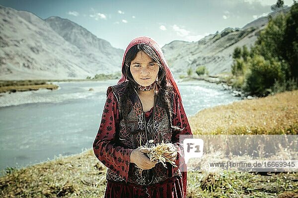 Girl 8 years bundles small wheat yarbs members of the ethnic group of the sedentary Wakhi Khandud Wakhan Corridor Afghanistan Asia