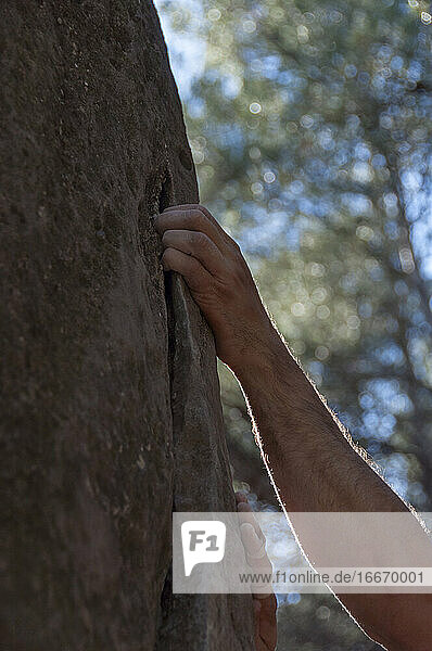 Der Arm eines Kletterers  der versucht  den Felsen zu erklimmen.