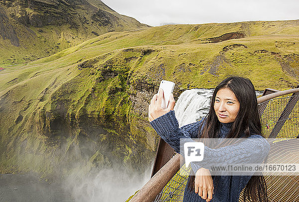 beautiful woman taking selfie at Skogarfoss waterfall in Iceland