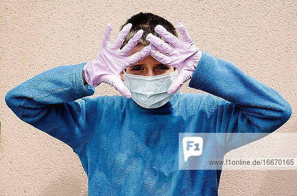 Ein blonder Junge mit Latexhandschuhen und Gesichtsmaske zeigt  wie er sich vor Coronaviren  Bakterien  Viren  Pilzen usw. schützt. Er hat Angst  sich bei einer Pandemie zu infizieren. Horizontal