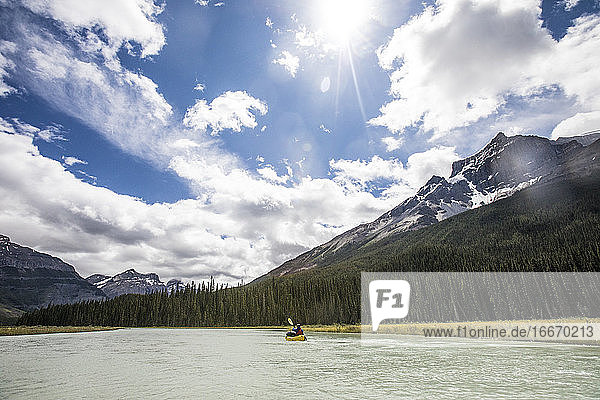 Fernblick auf eine Person  die in den Rocky Mountains mit einem Kajak (Packraft) paddelt.