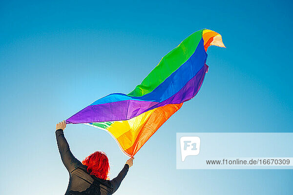 Junges Mädchen hisst LGBT-Flagge auf der Straße bei Tageslicht