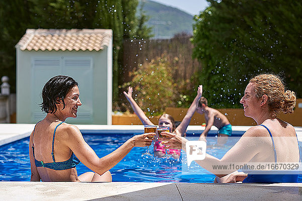Frauen in einem Pool. Sie stoßen an und feiern  dass sie im Urlaub sind.