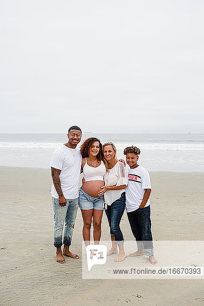 Familie posiert für Mutterschaftsfotos am Strand