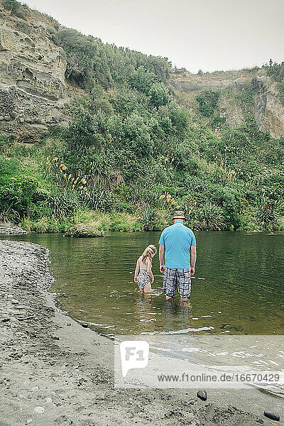 Vater und Tochter spielen im Wasser an einem malerischen Flussabschnitt