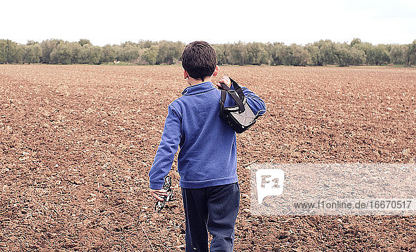 Junge läuft durch das Feld und nimmt seine Drohne mit  um sie zu blasen