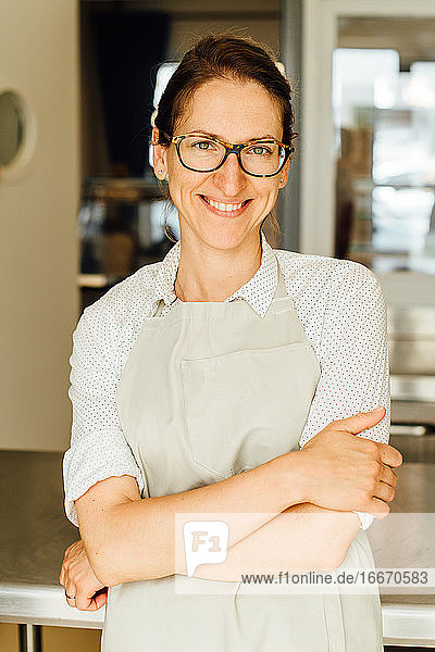 Porträt einer Köchin mit Brille und Schürze  die in die Kamera lächelt