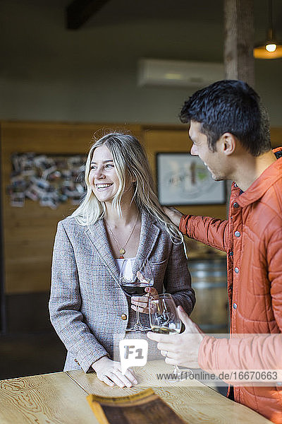 Ein junges Paar genießt Wein auf einer Terrasse eines Weinguts in Oregon.