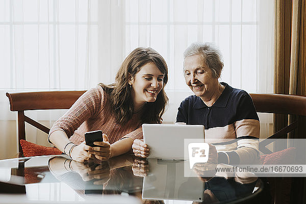 grandmother teaching her granddaughter something on the tablet