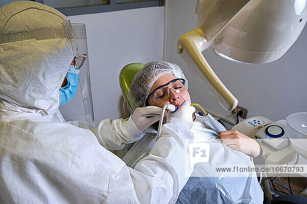 Zahnärztin beim Bohren eines Zahns für einen Patienten in einem geschlossenen Raum