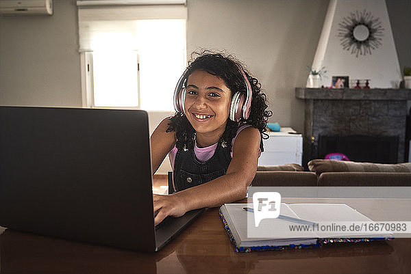 ein Mädchen lächelt  während sie von zu Hause aus mit ihrem Laptop lernt