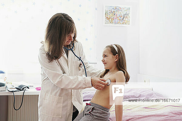 Seitenansicht eines Kinderarztes  der ein kleines  fröhliches Mädchen mit