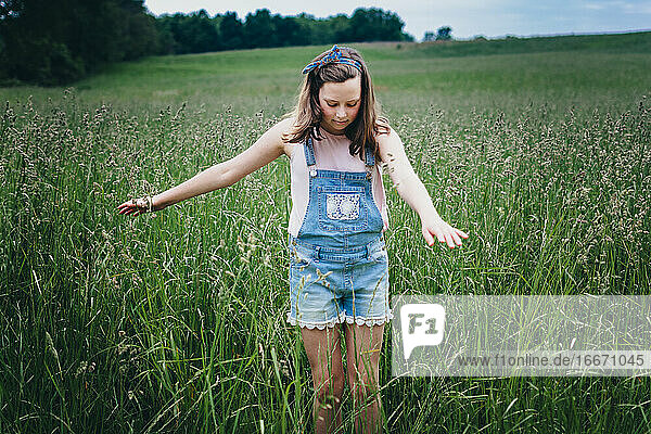 Teenager-Mädchen in einem Feld läuft ihre Hände durch das hohe Gras