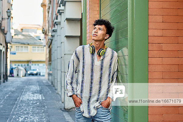 Junger afro-haariger Mann mit Kopfhörern schaut auf