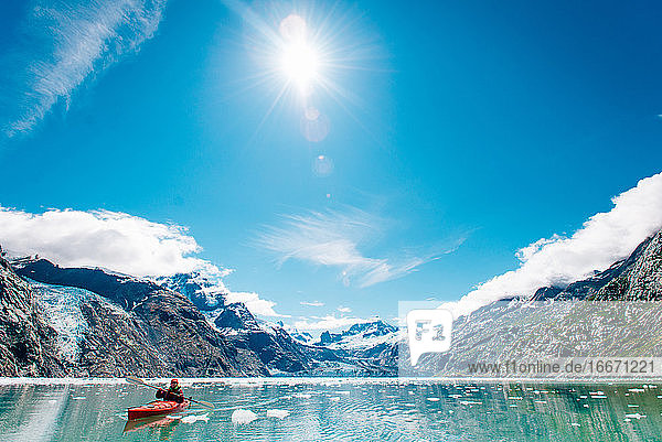 Woman kayaking in Glacier Bay National Park with glacier in background