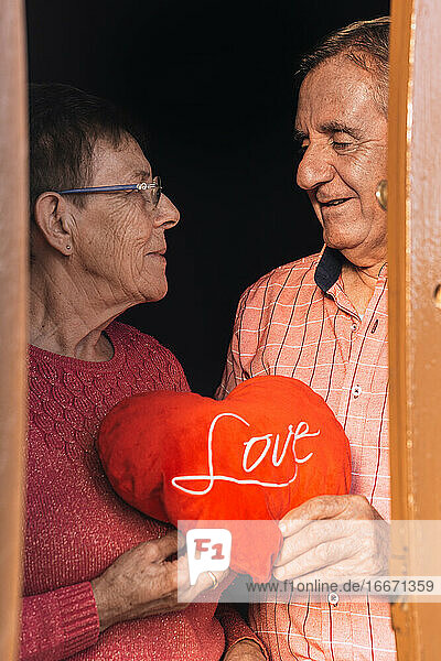 Glückliches liebendes älteres Paar mit rotem Herzgeschenk