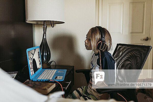Schulpflichtiger Junge beim Fernunterricht im Hotelzimmer während einer Pandemie