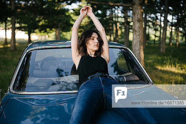 Porträt einer Hipster-Frau auf dem Auto sitzend