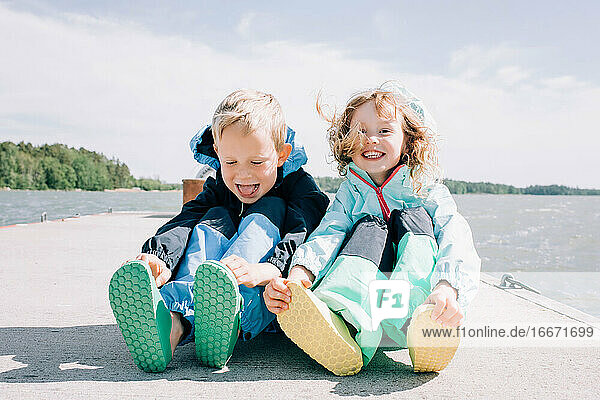 Bruder und Schwester saßen an einem windigen Tag am Strand und lachten zusammen