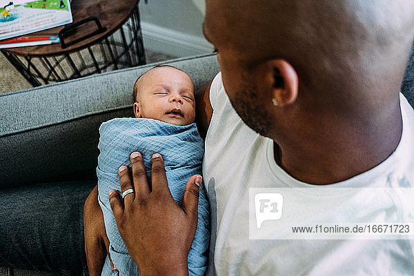 newborn baby sleeping in fathers arms