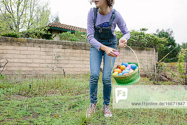 Teenager-Mädchen sammelt zu Ostern Plastikeier  um sie in ihren Korb zu legen