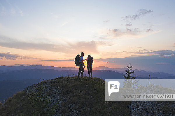 Paar Reisende Mann und Frau sitzen auf einer Klippe und beobachten den Sonnenuntergang